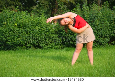 Girl doing exercise on grass. Bend right with hand up.