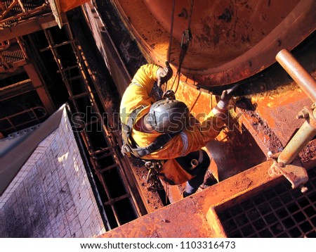 Rope access industrial technician miner fitters, boilermaker wearing fully safety harness, abseiling working maintenance inspecting cleaning chute roller isolated mining iron ore construction Perth