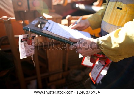 Rope access miner supervisor inspecting and checking name list on isolation permit holder box ensure all construction miners are locking on right permit prior to work on mine site, Perth, Australia