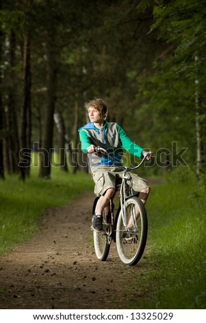 Caucasian young man on cruiser bicycle in forest