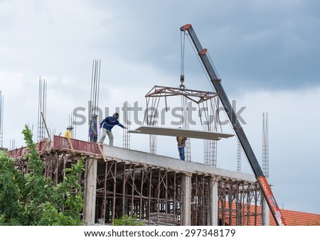 NAKHONRATCHASIMA.THAILAND-2015 JULY  16:Construction worker navigating with concrete slab lifted by crane at building site