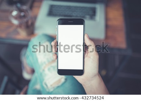 girl using smartphone in cafe. hand holding smartphone white screen. black color smartphone vintage tone.