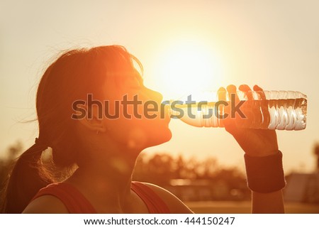 Female drinking a bottle of water. Girl drinking a water. Woman drinking a water. girl drinking a water on sunset. Closeup woman drinking a water.Thirst by drinking water. Rush finished drinking water