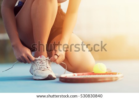 Tennis player tying shoelaces in tennis court at Thailand.