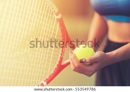 Player\'s hand with tennis ball preparing to serve in tennis cort.