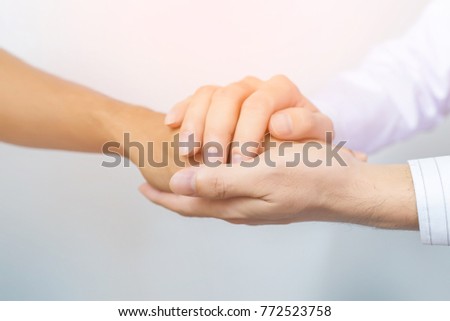 Two people holding hands for comfort. Doctor consoling relatives of patients in hospital concept
