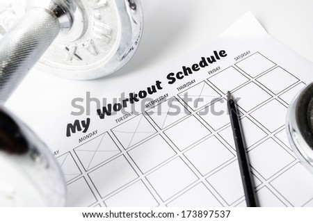 Workout schedule sheet and dumbbell on white background.