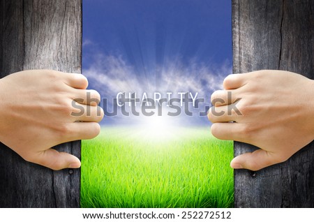 Charity and Non profit concept. Opening a door and see Charity word floating with Sun rise on a green field & blue sky.