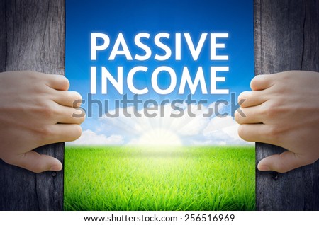 Passive Income. Hand opening an old wooden door and found Passive Income word floating over green field and bright blue Sky Sunrise.