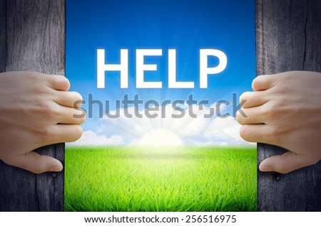 HELP. Hand opening an old wooden door and found HELP word floating over green field and bright blue Sky Sunrise.