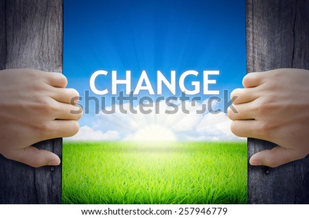 Change. Hand opening an old wooden door and found Change word floating over green field and bright blue Sky Sunrise.