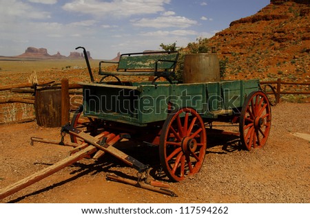 Old farm wagon in front of the fantastic shapes of the vast sandstone buttes of Monument Valley, part of the Colorado Plateau in the Navajo Nation Reservation, from Gouldings Lodge, Utah, USA