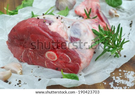 leg of lamb with salt, garlic, rosemary and baby spinach on a wooden background