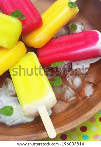 berry, lime and orange ice creams with ice cubes and mint leaves