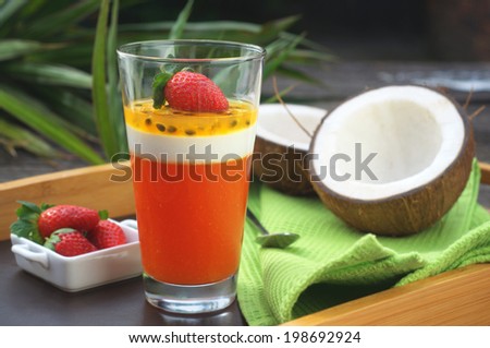 papaya, coconut and passion fruit parfait with a fresh strawberry on a top