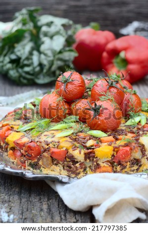 red rice and vegetables pie with roasted tomatoes on a top