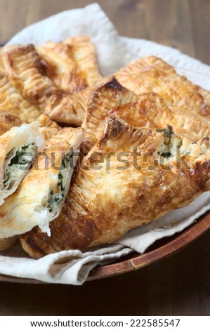 Spinach and ricotta pasties on a bamboo plate and on a wooden background