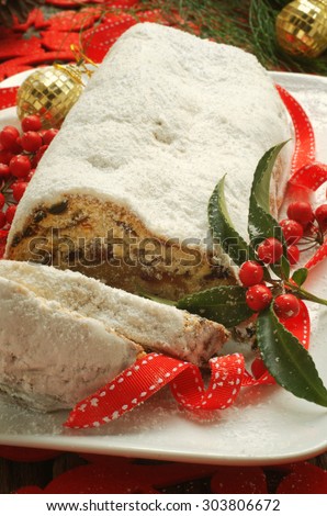 traditional German Christmas cake/stollen with some berries and ribbon on a white platter. selective focus