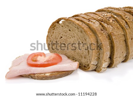 Slices of granary bread and sandwich with ham and tomato on white background
