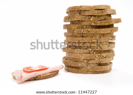 Stack slices of granary bread and sandwich with ham and tomato on white background