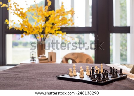Chess in bed, yellow flower in the window.