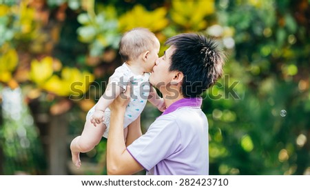 father kissing and try to lift his 7 months baby for make her happy.