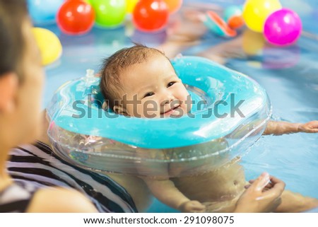 Mother try to train her 7 months baby to swim in the small pool.
