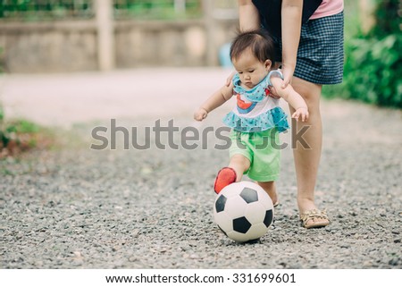 Mother practices her child to play a soccer football.