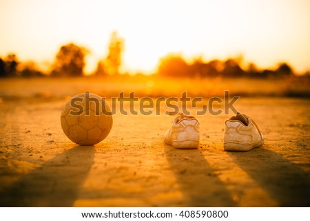 an old ball with the shoes for street soccer football under the sunset ray light.