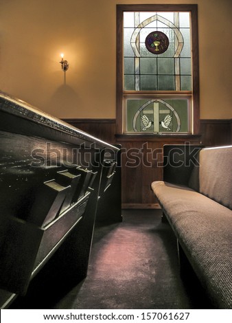 sunlight falls across pews in a small church from stained glass window and light of small wall