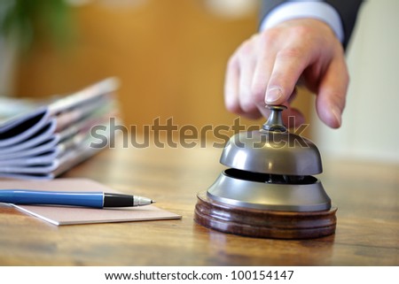 Businessman ringing a hotel reception service bell to attract attention