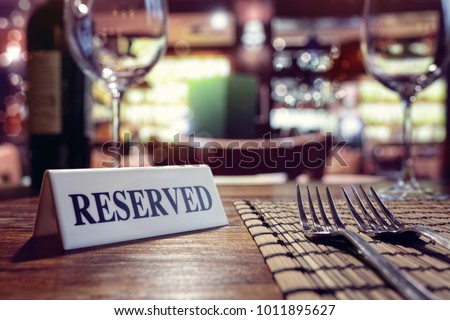 Restaurant reserved table sign with places setting and wine glasses ready for a party