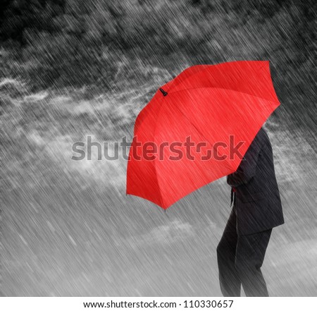 Businessman with red umbrella protecting himself from the storm concept for protection from recession or economic depression etc