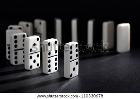 Dominoes lined up ready to fall concept for domino effect, balance and risk