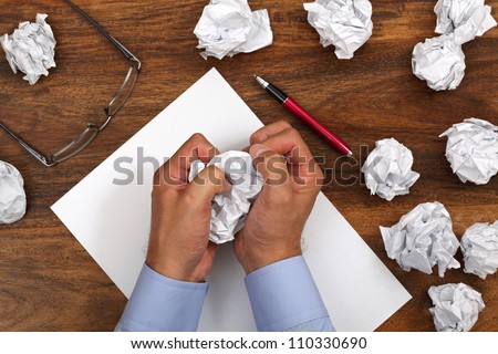 Crumpled paper and businessman tearing up another paper ball for the pile