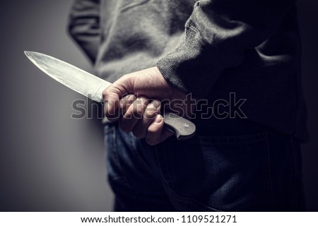 Criminal with knife weapon hidden behind his back