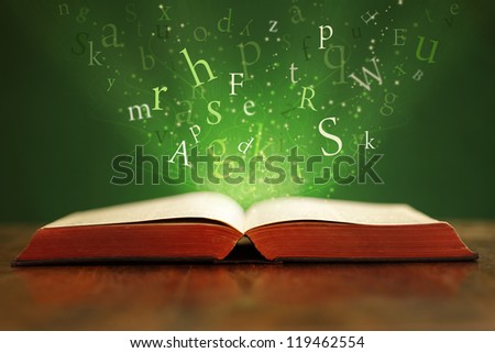 Book or bible on table with flying letters on green background