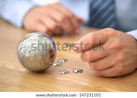 Businessman Solving Globe Puzzle Concept For Business Solutions And Strategy