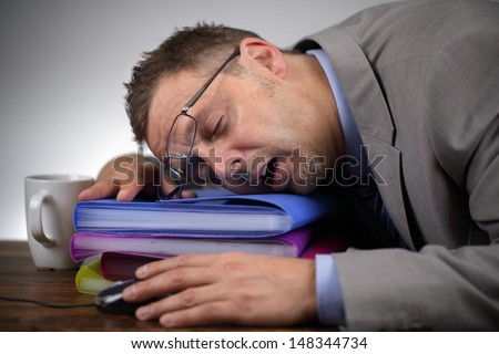 Exhausted businessman falling asleep at his office desk