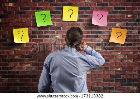 Choice And Decisions: Businessman Thinking With Question Marks Written On Adhesive Notes Stuck To A Brick Wall