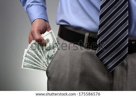 Businessman with money in suit trouser pocket concept for business wealth, paying, corruption or bribing
