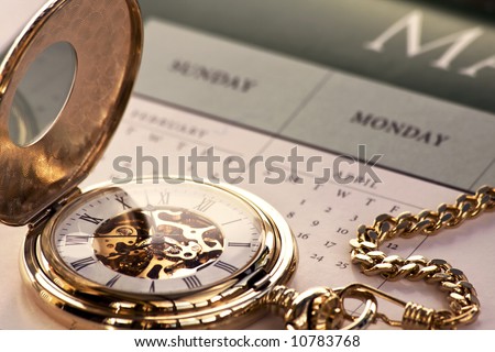 Close up of a gold pocket watch on a calendar