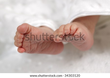 Tiny feet of a newborn baby with his toes curled up