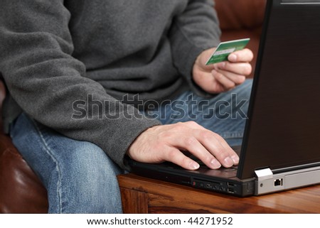 Casual man at home using a laptop computer for internet shopping and ordering online with a credit card