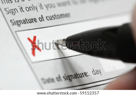 Hand holding a pen ready to sign a contract in the box by the red cross