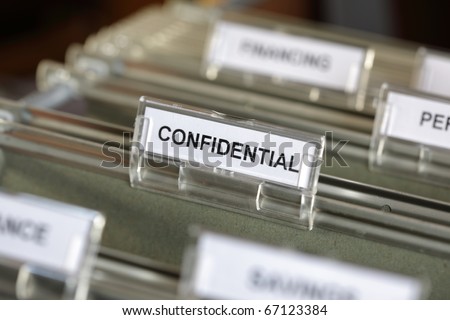 Inside of a filing cabinet with green folders and focus on confidential label