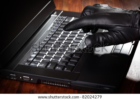 Burglar stealing data from a laptop concept for computer security, corporate or identity theft