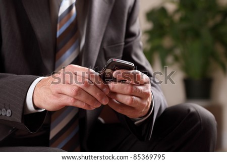 Text messaging or checking email on mobile phone whilst waiting for a business meeting