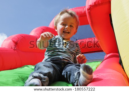 2 year old boy jumping down the slide on an inflatable bouncy castle