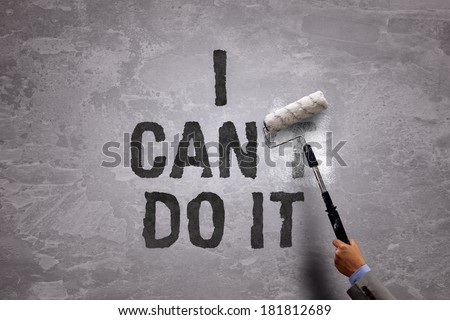 Changing the word can\'t to can by painting over and erasing part of it with a paint roller on a concrete wall in the phrase i can do it